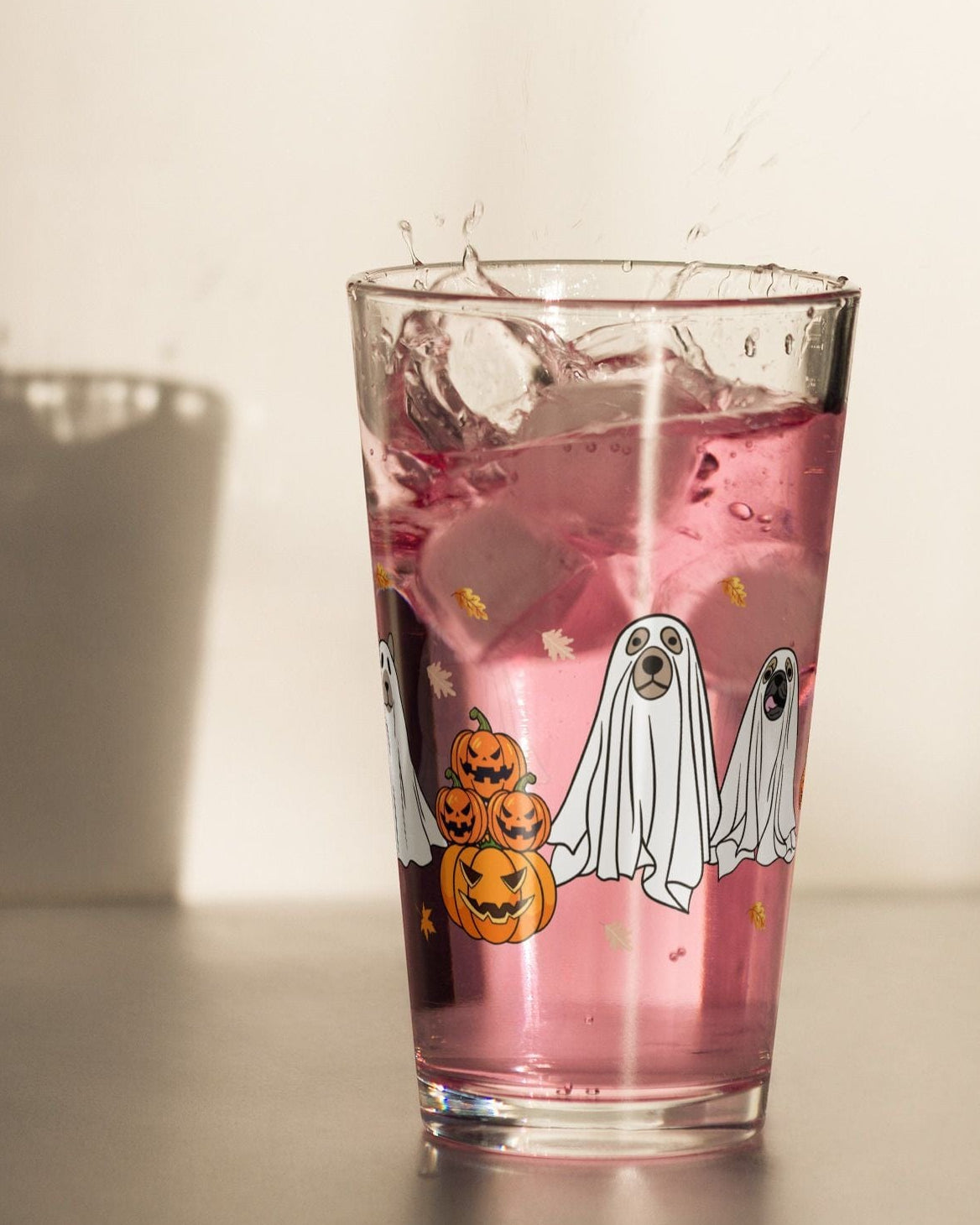 16oz Halloween cocktail glass filled with a pink beverage and adorned with ghost illustrations